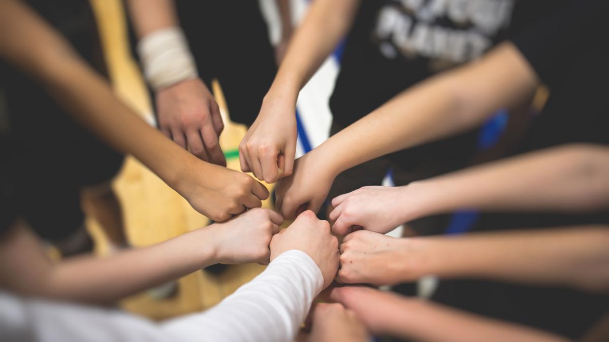 A close up of youth fists together during a youth sports team event.