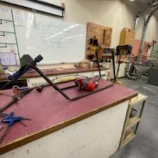 A shop work bench with a mini-bike frame and engine ready to be assembled.