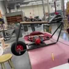 A shop work bench with a mini-bike frame and engine ready to be assembled.