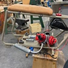 A shop work bench with a mini-bike frame and engine ready to be assembled.