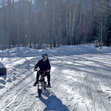 A high school student rides a mini-bike through a snowy parking lot. 